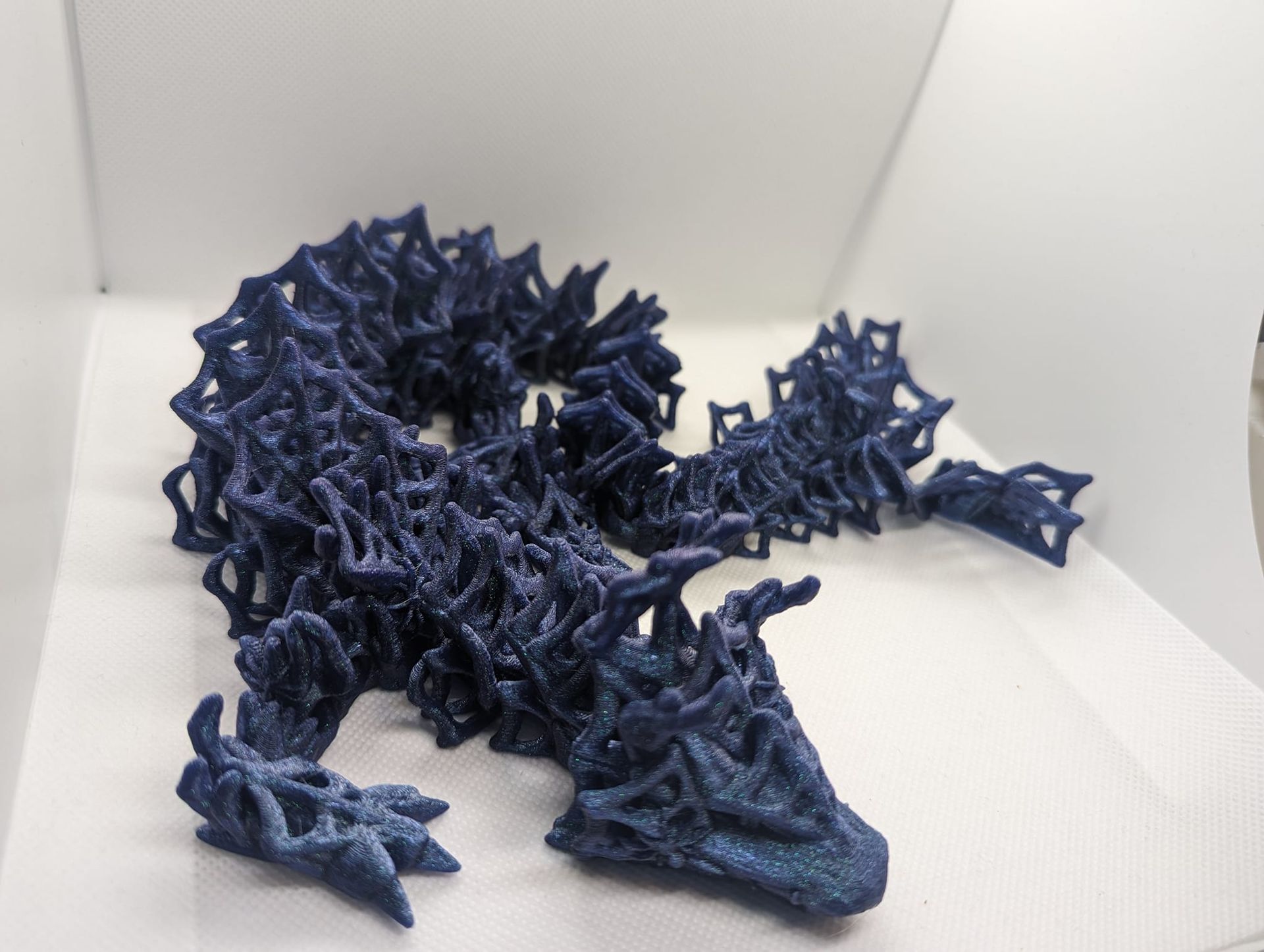 Blue spiky dragon figurine posed on a white surface with a coiled tail and open mouth