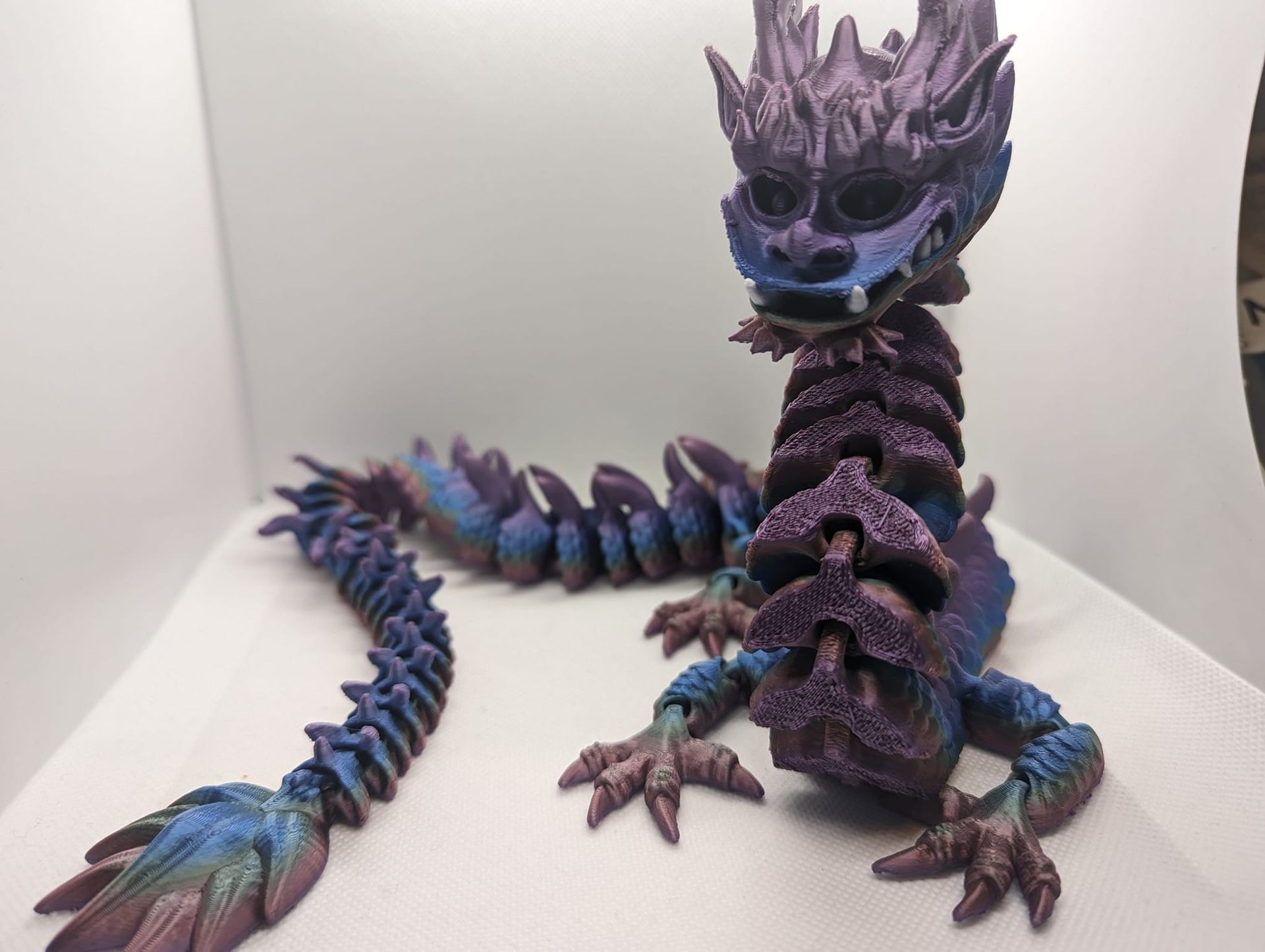 Purple-blue dragon figurine with spined tail, posed on a white backdrop