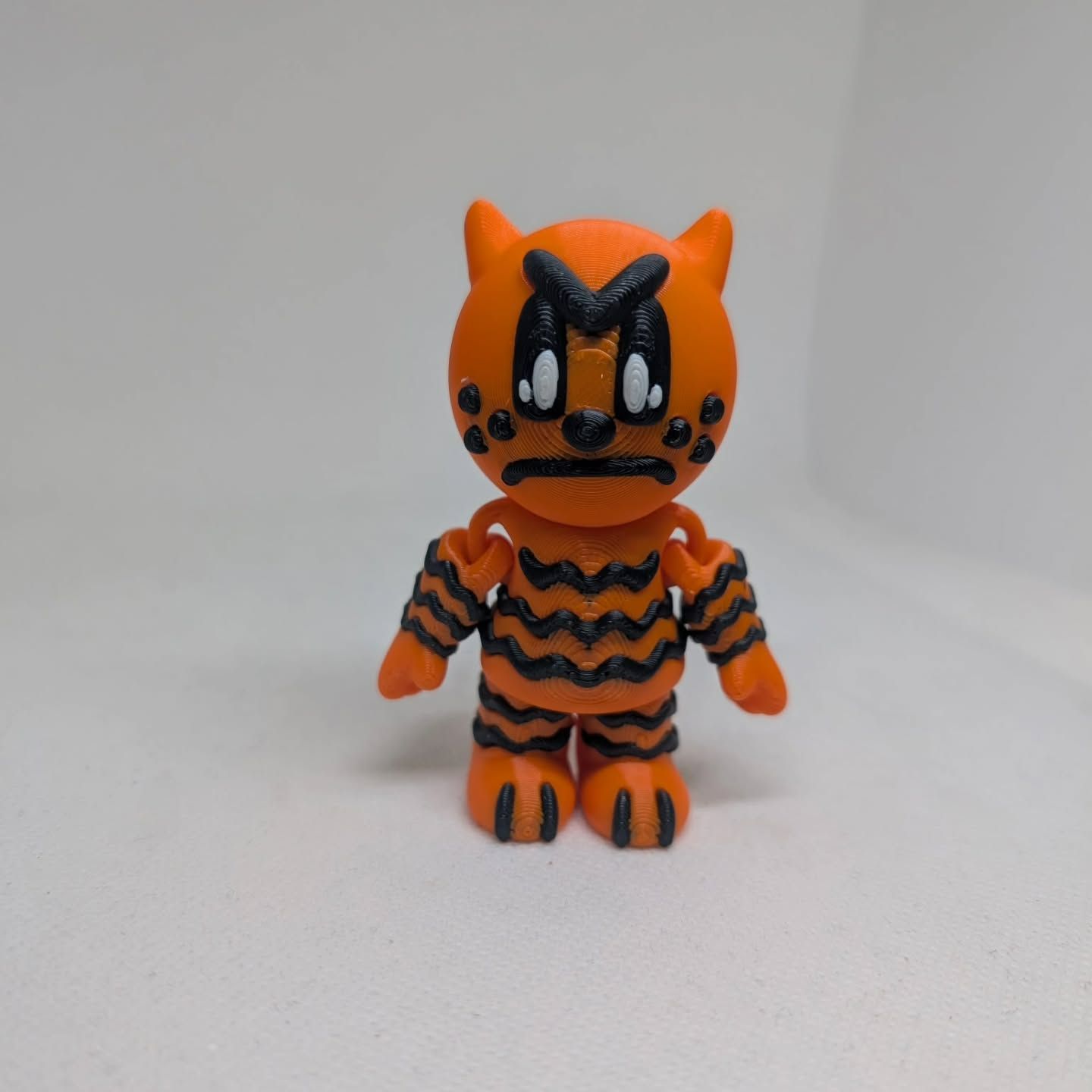 Orange-and-black striped cat figurine standing on a white background, front view