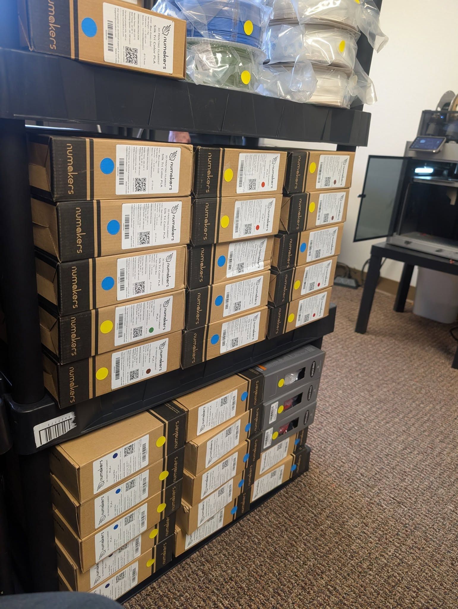 Shelves stacked with many cardboard boxes in a storage room with carpeted floor and plastic-wrapped items on top