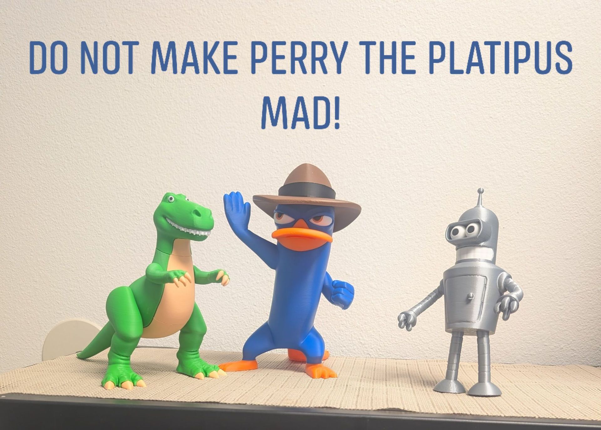 Text reading “DO NOT MAKE PERRY THE PLATYPUS MAD!” above Perry, a green dinosaur, and a silver robot.