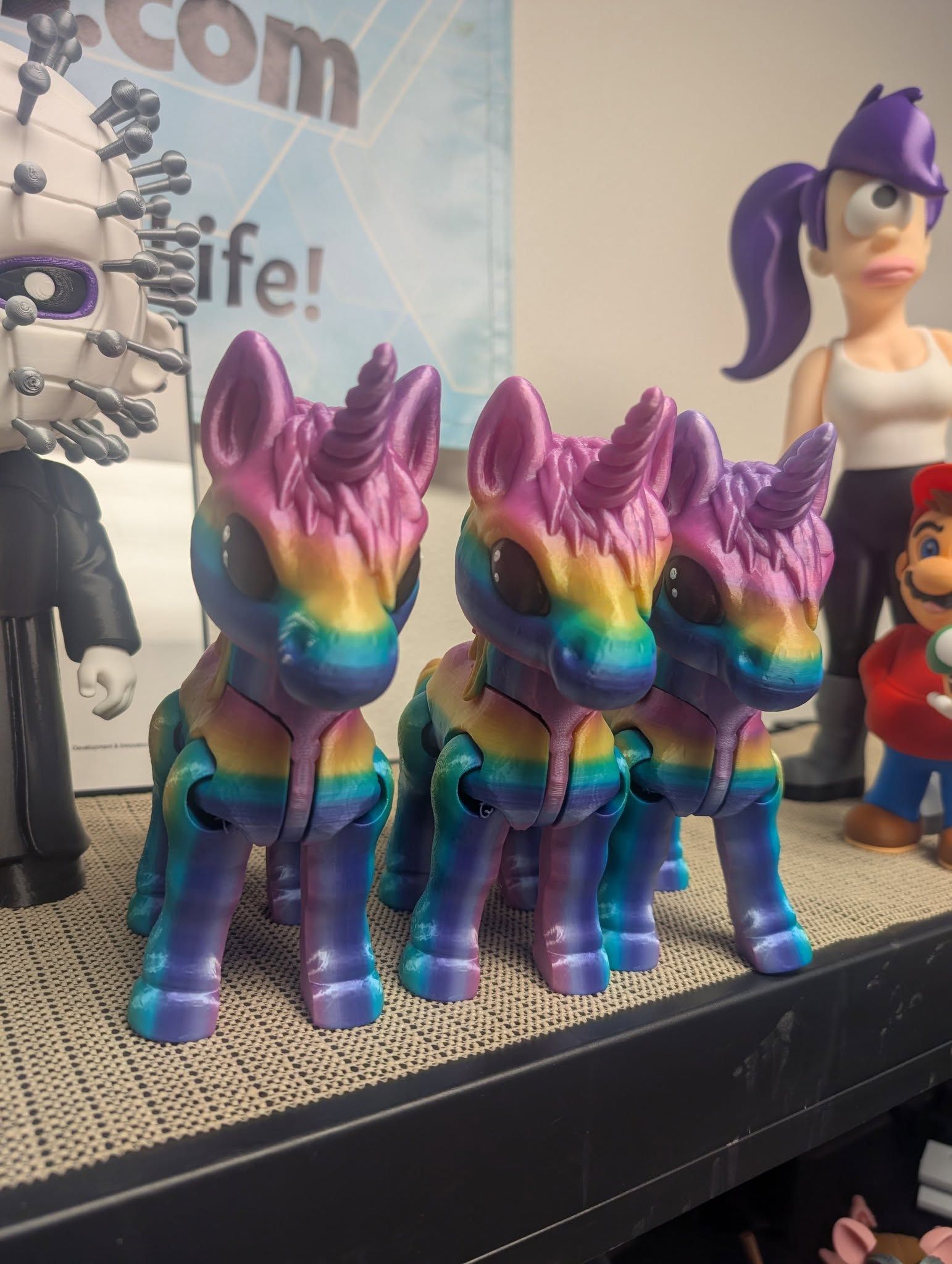 Rainbow-striped unicorn figurines on a shelf beside a purple-haired toy character.