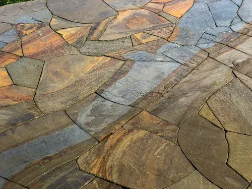 Close-up of multicolored stone paving with irregular geometric slabs in gray, tan, and brown tones
