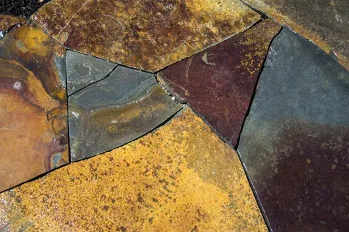 Abstract mosaic of irregular stone tiles in gold, blue-gray, maroon, and black tones