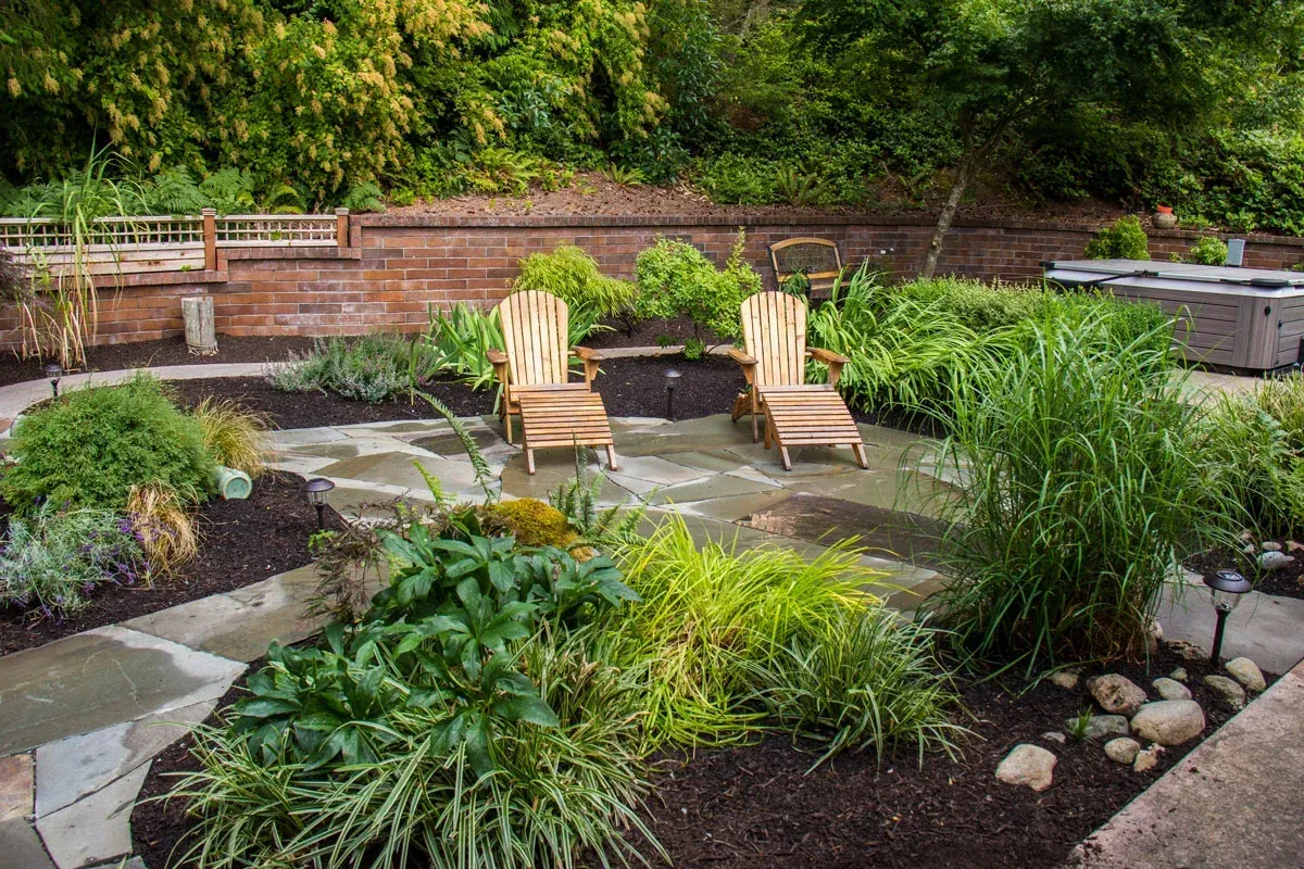 Backyard flagstone walkway and lounge chairs by a small pond after a garden makeover
