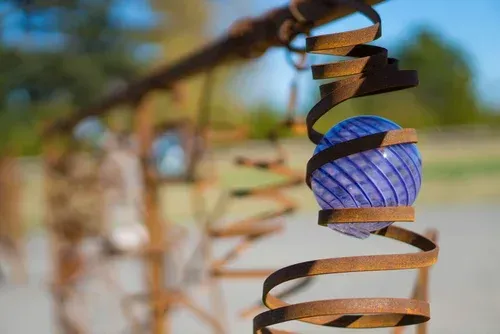 Blue hanging lantern wrapped with spiral metal against a blurred outdoor background