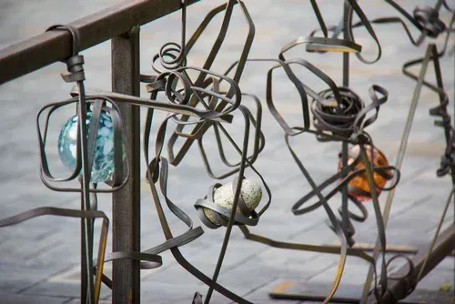 Abstract metal sculpture with wire loops and colorful glass orbs outdoors