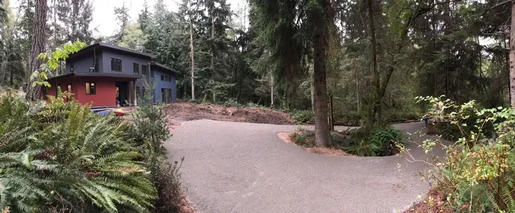 Winding driveway by a red cabin in a wooded forest setting