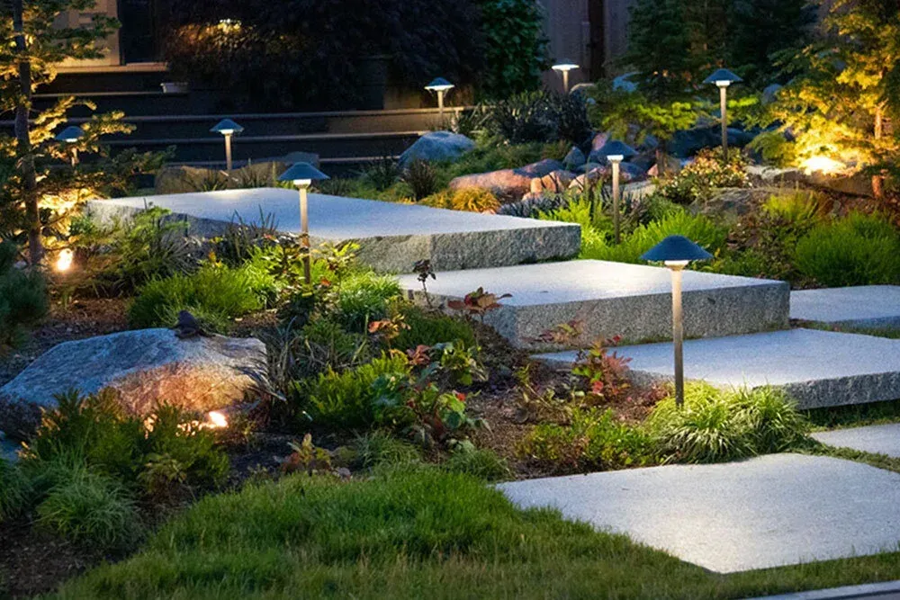 Illuminated stepping-stone path through a landscaped garden at dusk