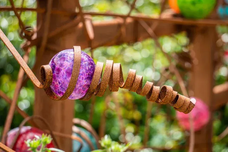 Purple and brown spiral ornament hanging outdoors against a blurred green background