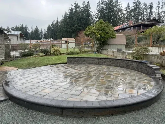 Circular paver patio with a curved block seat wall in an Oak Harbor backyard