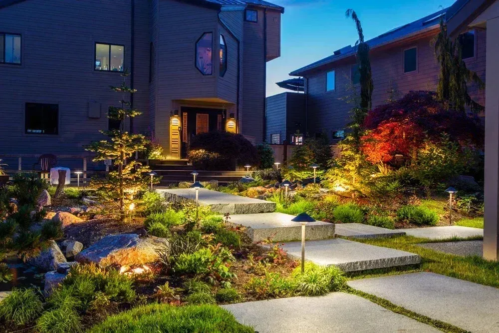 Seaside entrance garden with lit stone paths at dusk, Whidbey Island landscaping by Creative Gardens