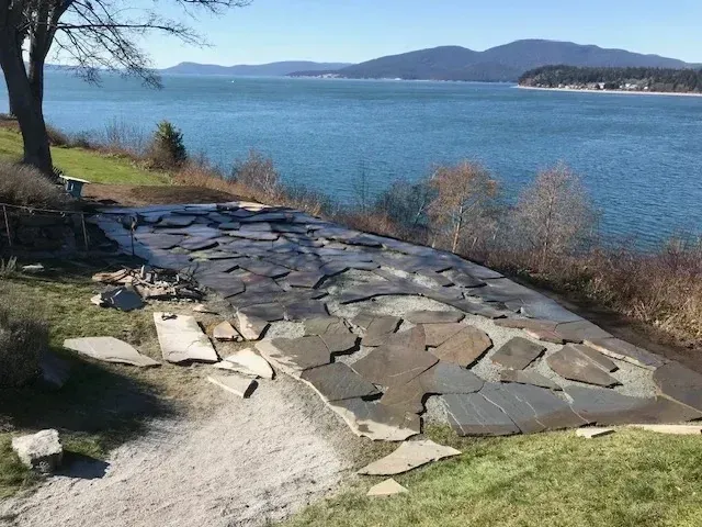 Flagstone patio being laid on a waterfront bluff overlooking the bay and island hills