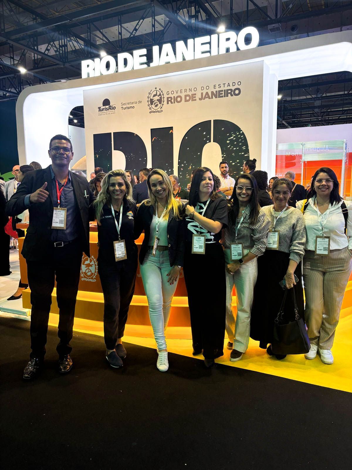 Grupo de pessoas posando em frente a uma placa com o nome 