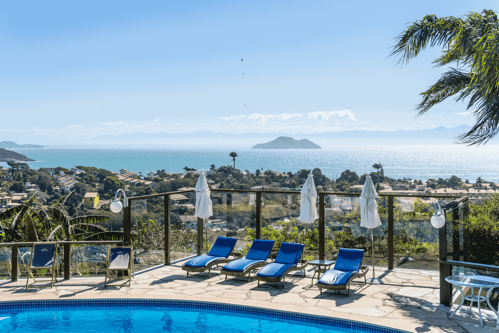 Piscina com vista para o oceano, equipada com espreguiçadeiras e guarda-sóis.