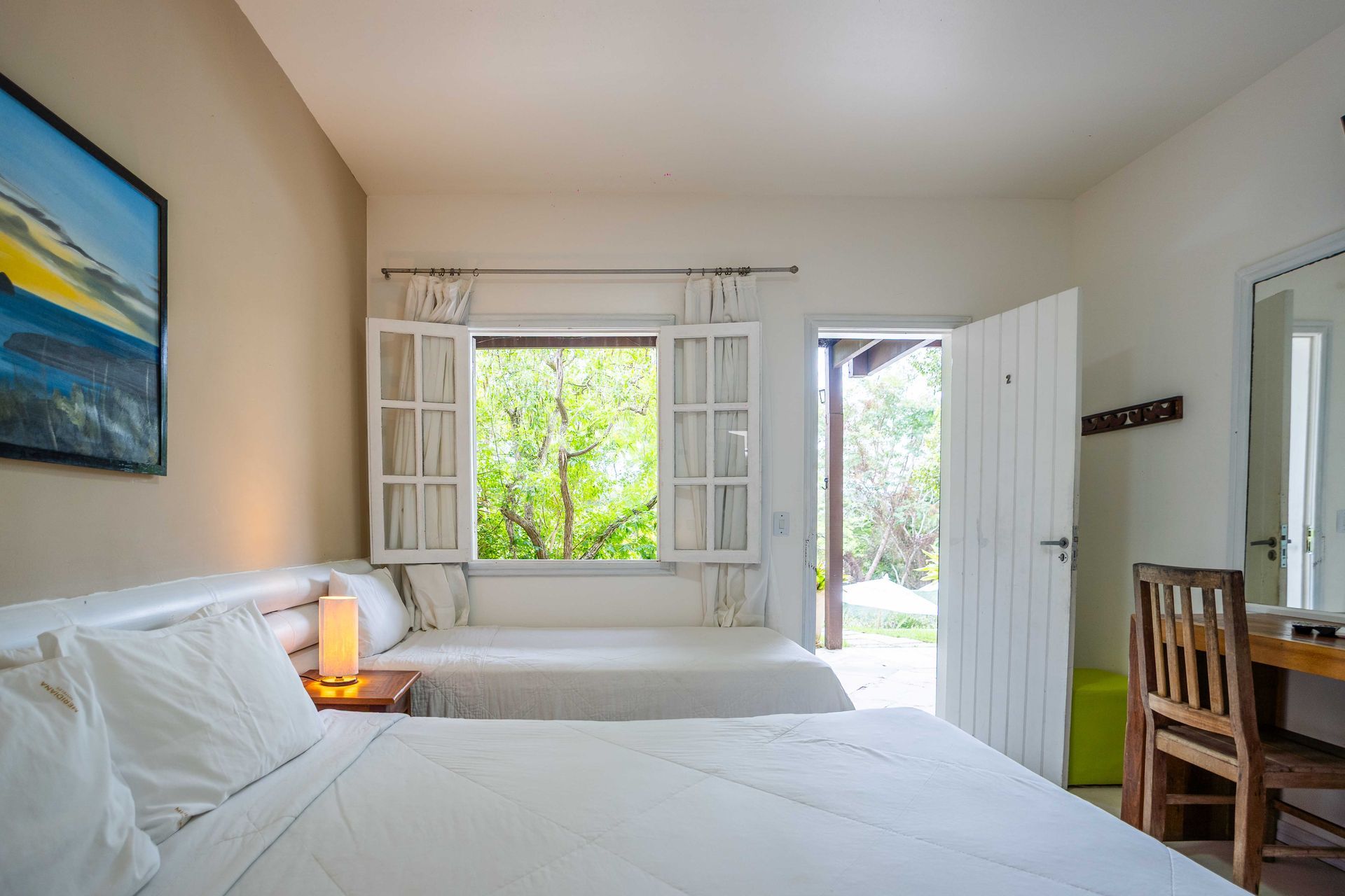 Quarto com duas camas, janela aberta com persianas e porta aberta para o exterior.