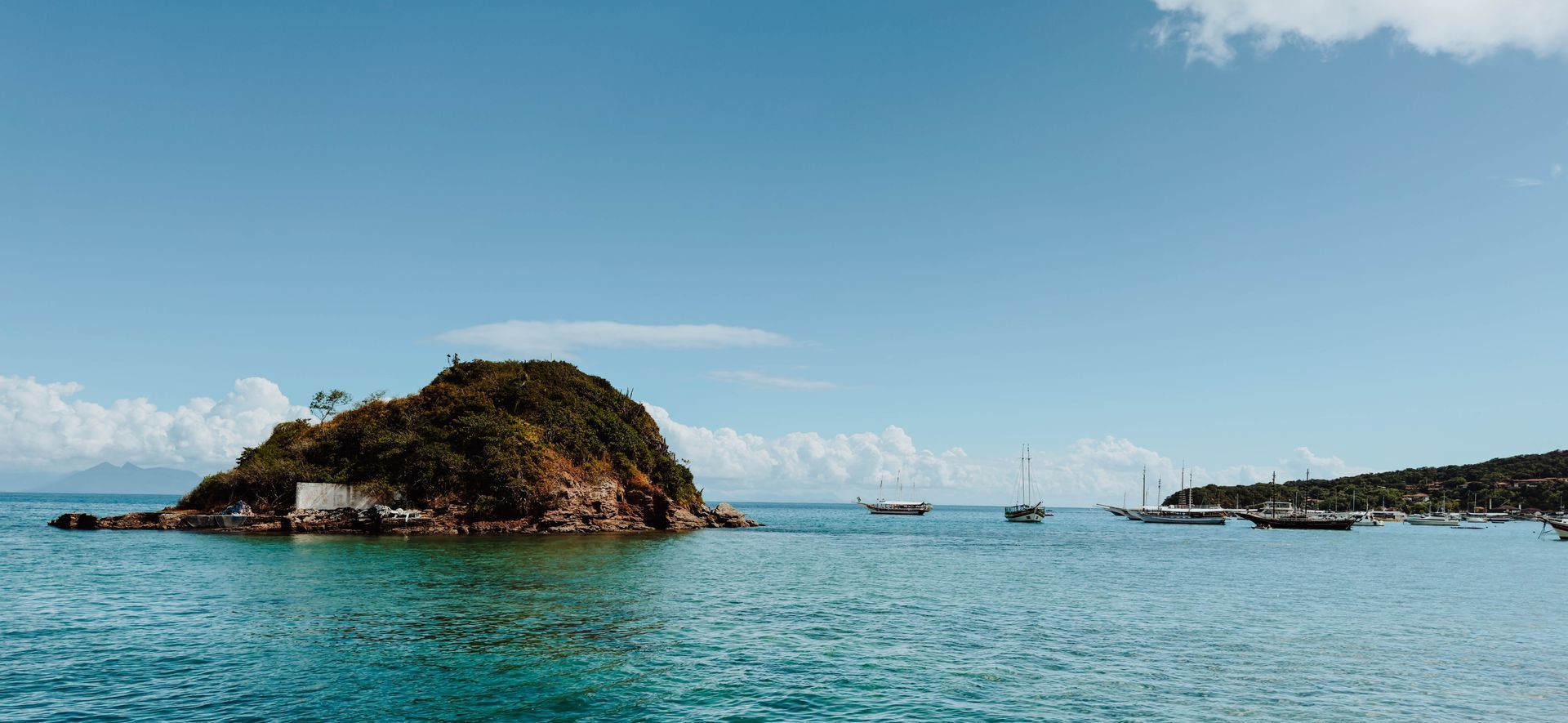 Uma ilha com vegetação exuberante, rodeada por águas turquesa sob um céu azul.