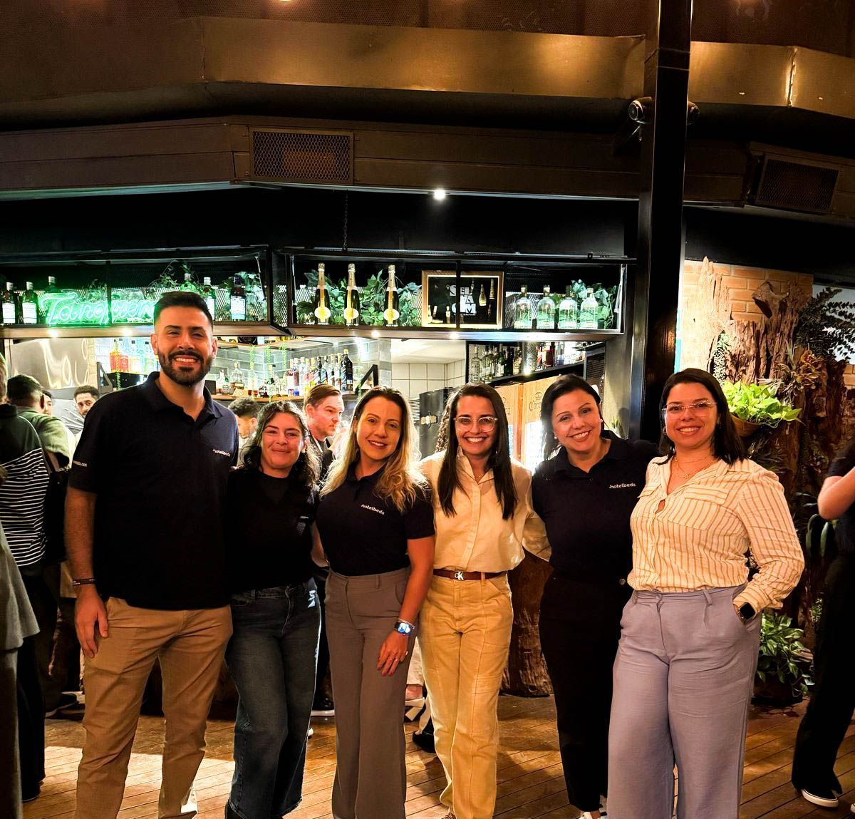 Grupo de pessoas sorrindo do lado de fora de um restaurante, à noite.