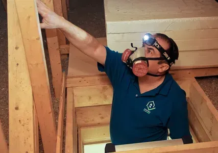 Un homme portant un masque à gaz et une lampe frontale travaille sur une structure en bois.