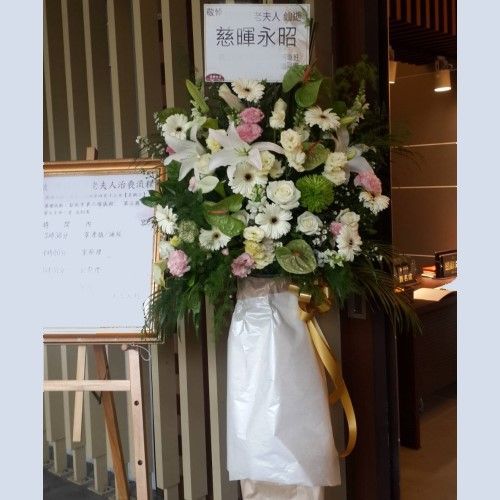 由白色、粉紅色和綠色花朵組成的花束，以及一塊寫有日文的牌子。