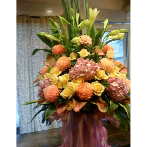 以粉紅色、黃色和橙色為主色調的花束，包含百合、玫瑰和菊花。