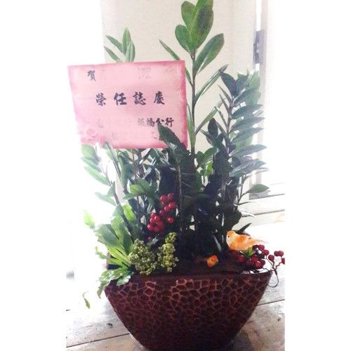 棕色花盆裡的插花，配上粉紅色卡片、紅色漿果和小鳥裝飾。
