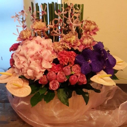 以粉紅色繡球花、紫色蘭花和其他色彩鮮豔的花朵組成的插花作品。
