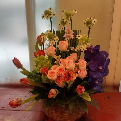 插花：棕色籃子裡裝著鬱金香、玫瑰、蘭花和其他花卉。