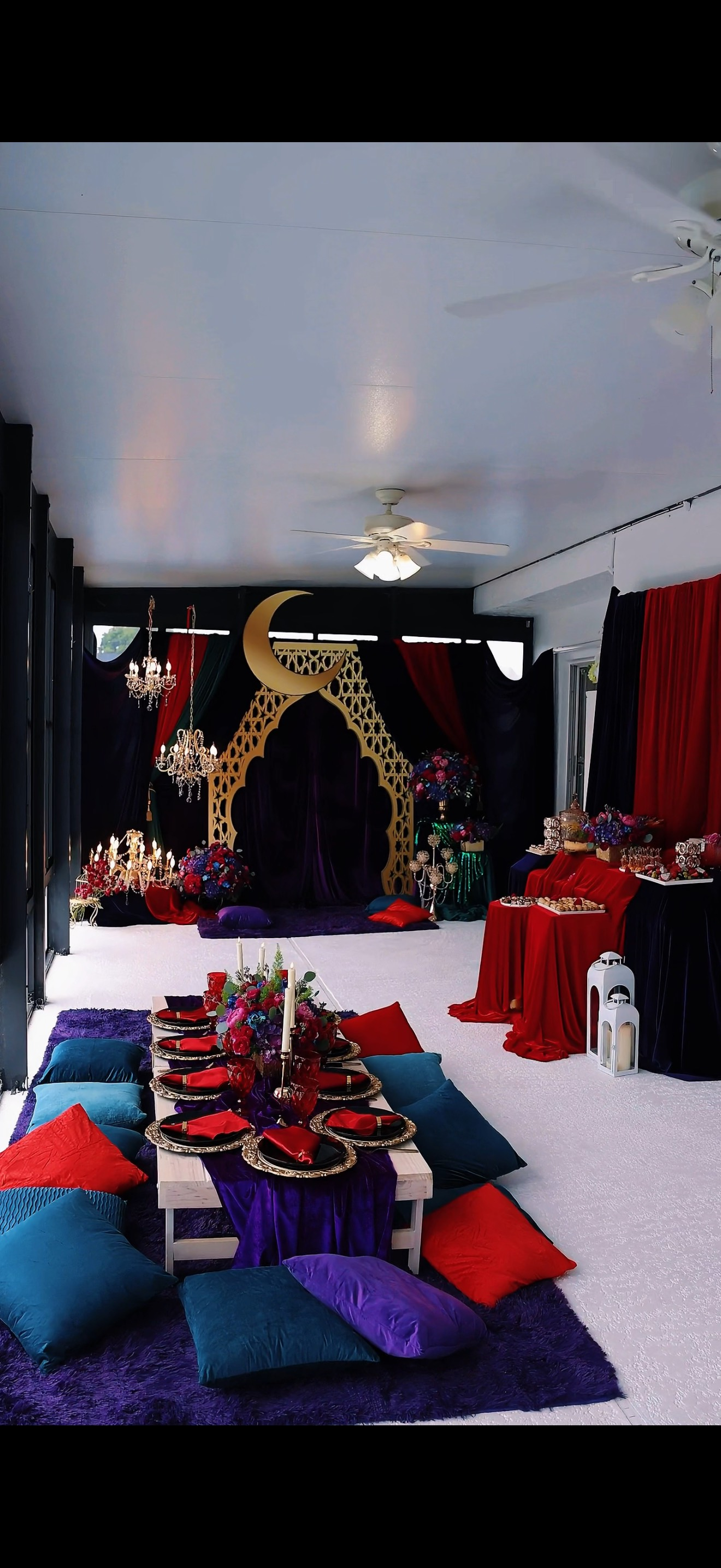 A festive, low table setting with colorful pillows and a moon-shaped archway in the background.