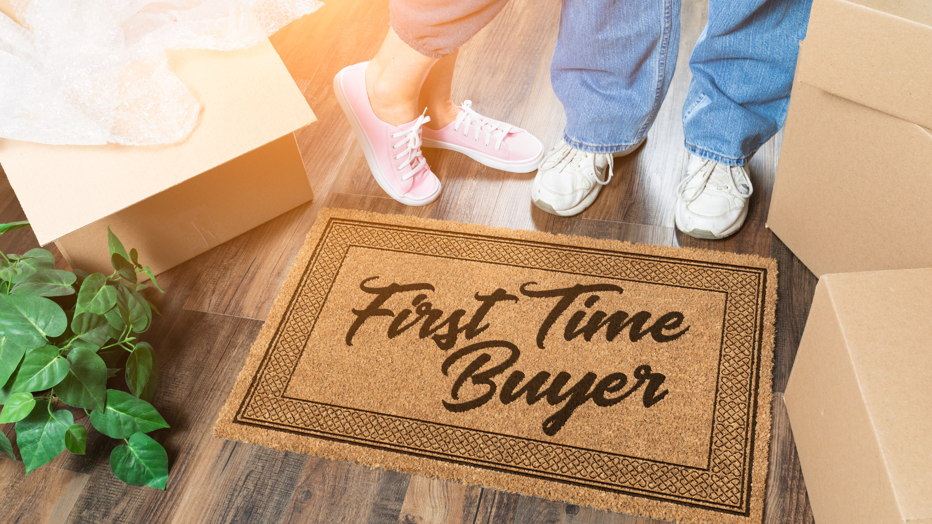 Two pairs of feet next to a doormat that says First Time Buyers