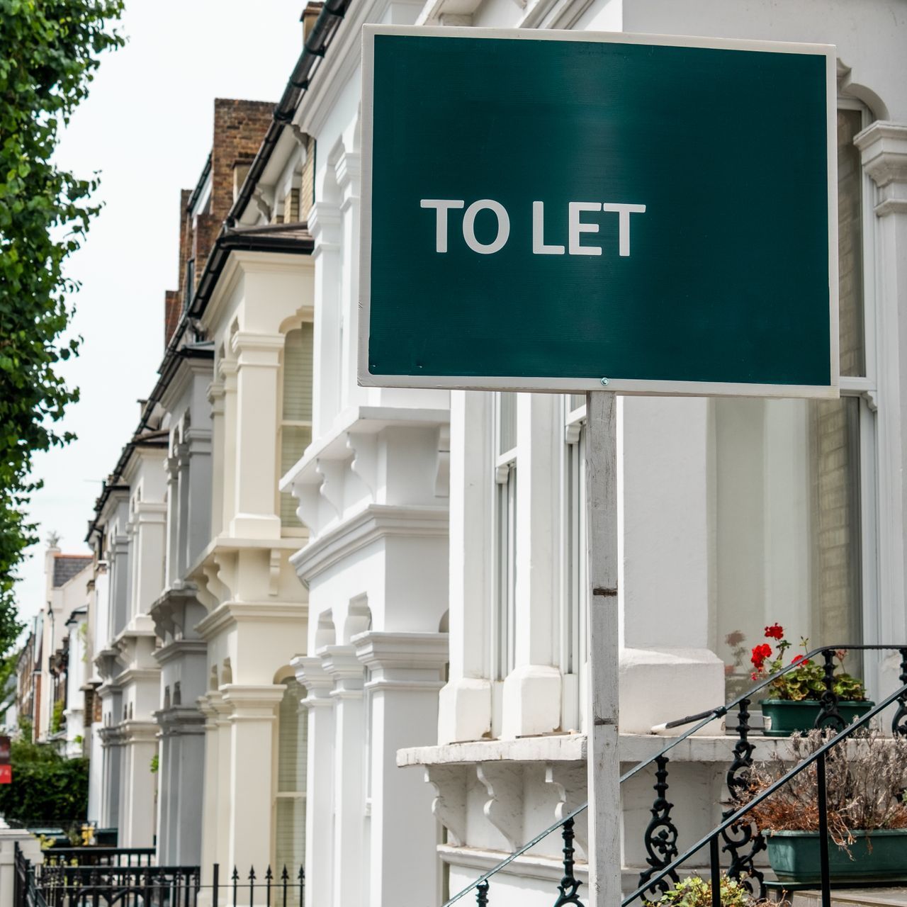 A green to let sign in front of a row of white houses
