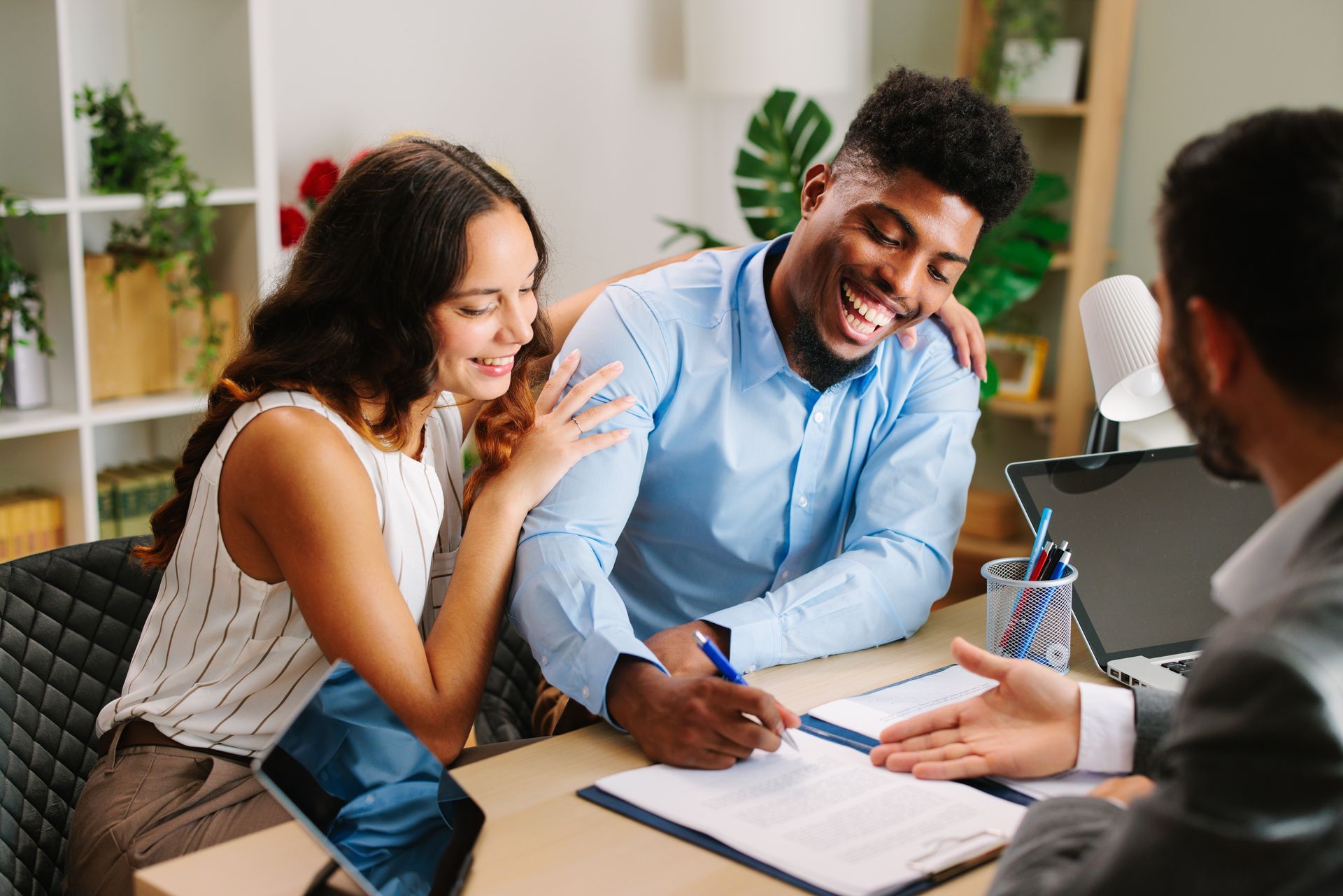 A young couple are smiling while receiving advice from a mortgage adviser about buying their first home
