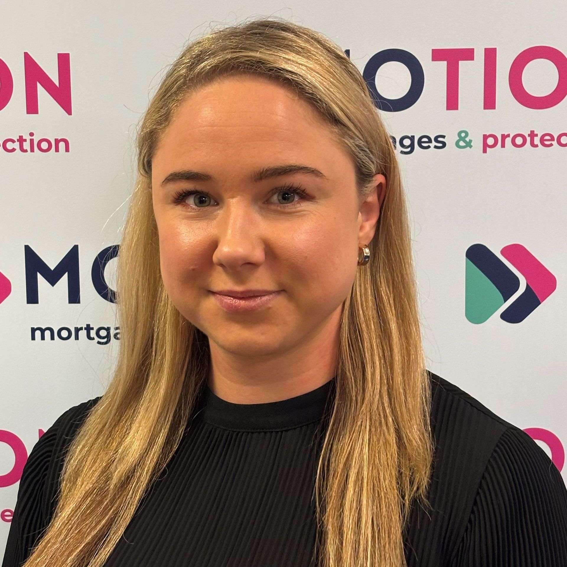 Angelika Stawarz of Motion Mortgages & Protection is smiling in front of a branded backdrop