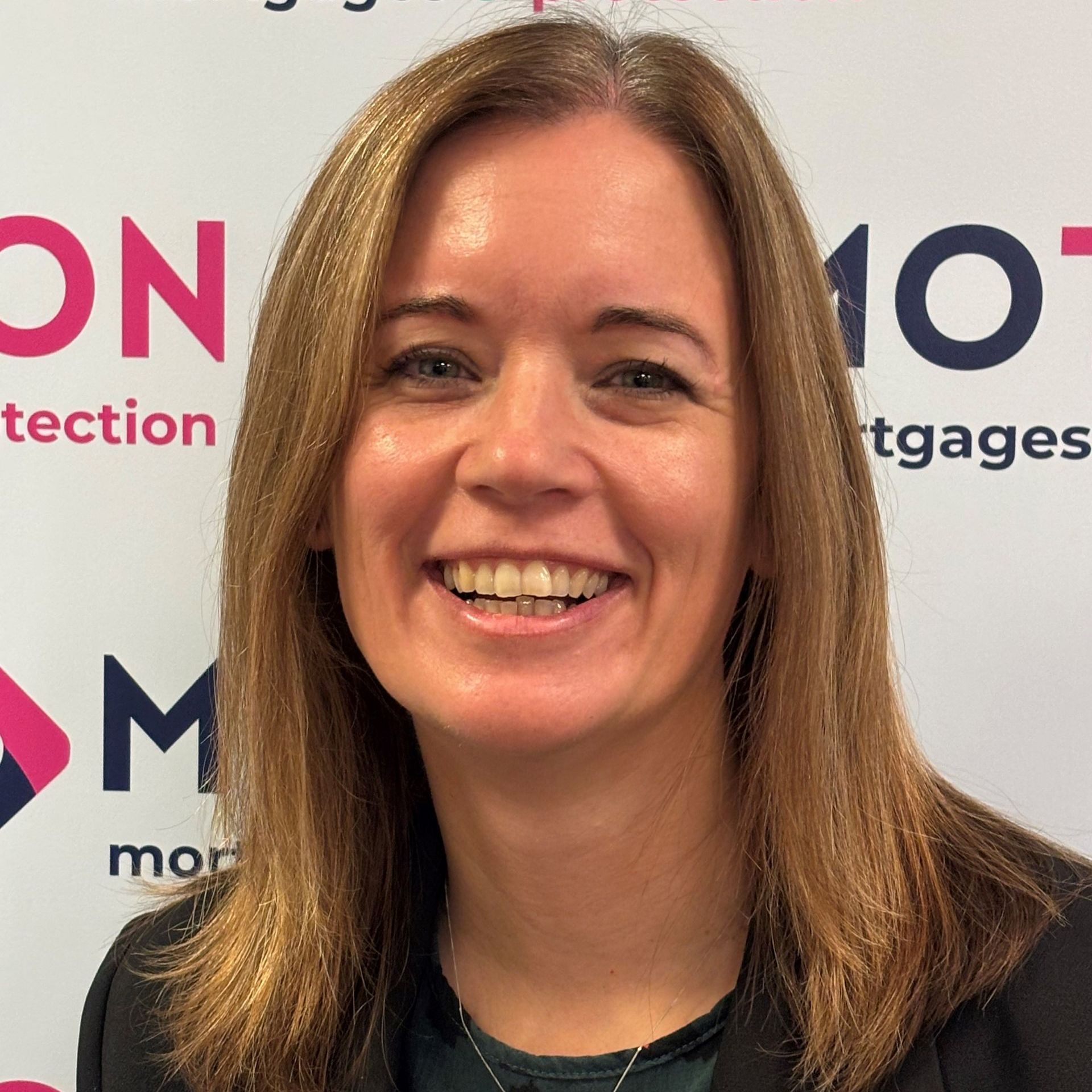 Emma Reynolds of Motion Mortgages & Protection is smiling in front of a branded backdrop