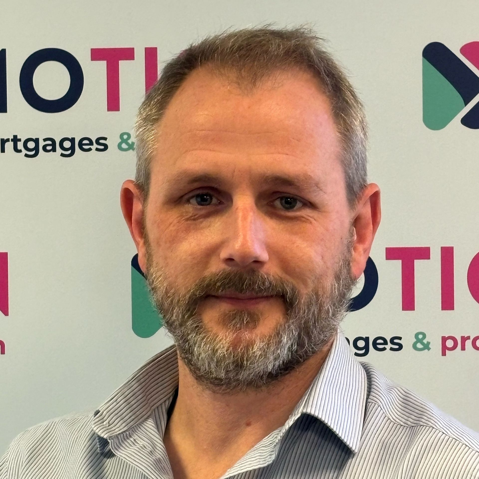 Russell Clark of Motion Mortgages & Protection is smiling in front of a branded backdrop