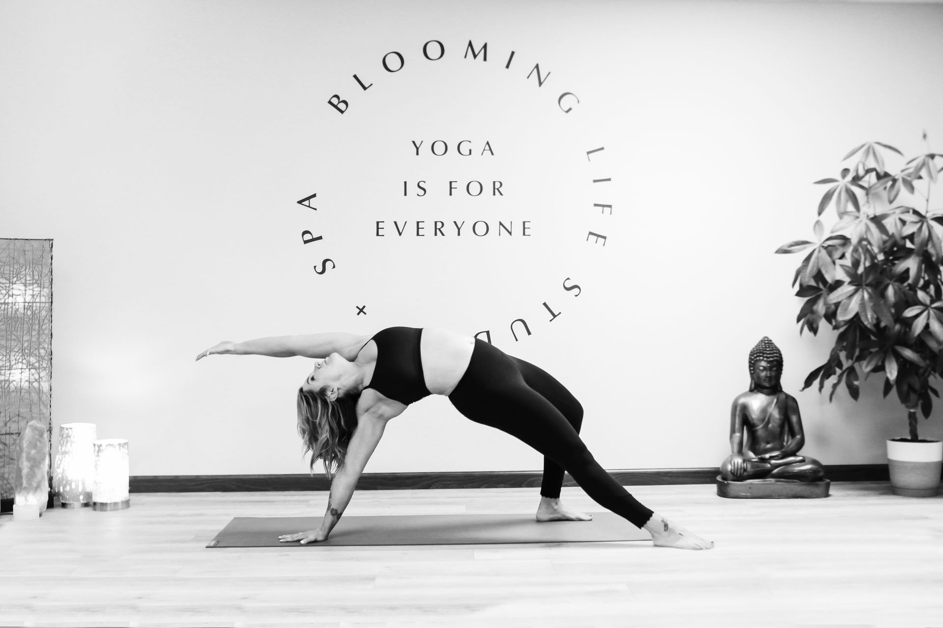 Woman in a yoga backbend pose in a bright studio with wall art and plants