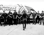 Group standing in front of a black van with “Covenant Plumbing” signage, one person walking toward them.