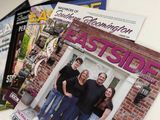 Stack of Eastside magazines with a smiling group on the cover