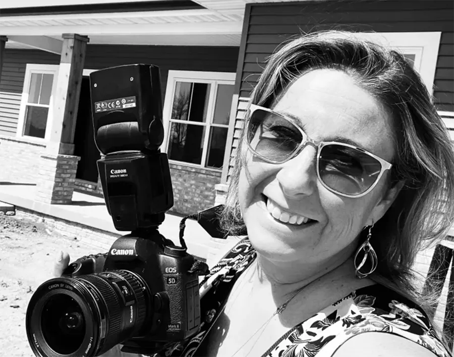 Woman holding a camera in front of a house
