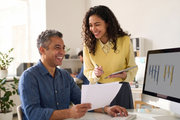 Two coworkers reviewing a chart at a desk in a bright office