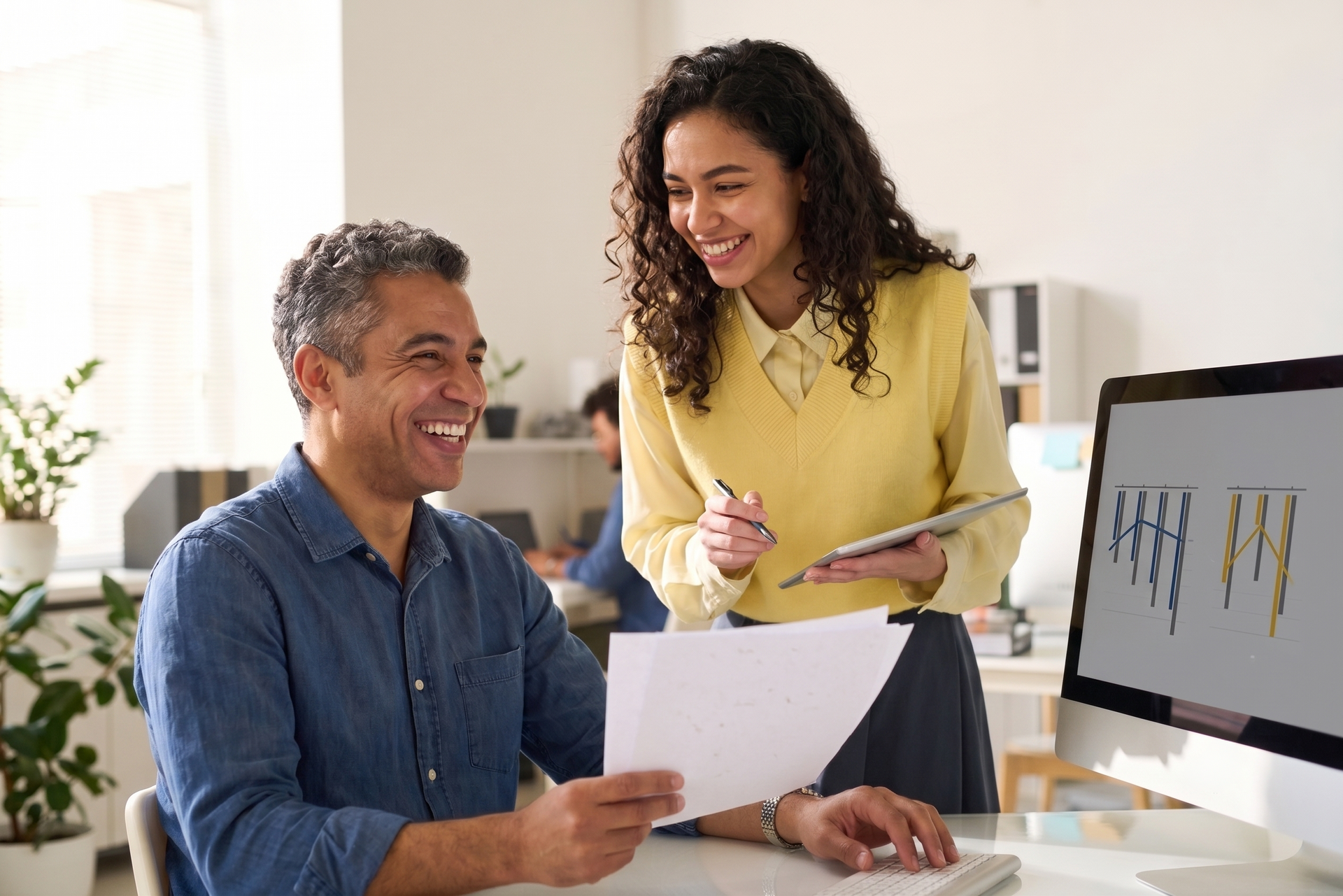 Two coworkers reviewing a chart at a desk in a bright office