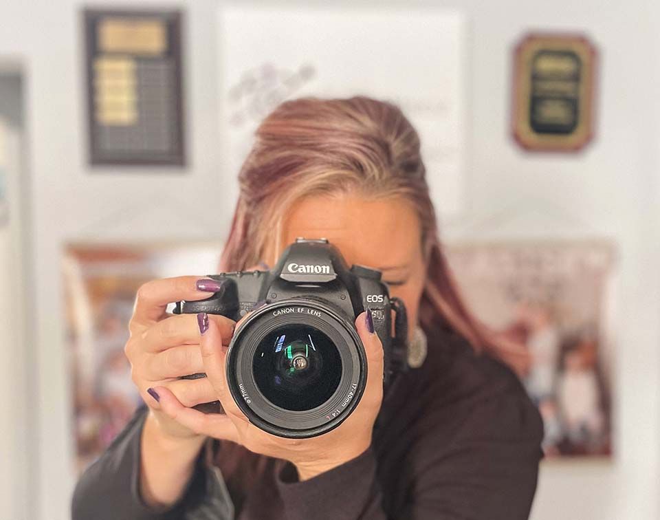 Person holding a Canon camera up to their face in a home interior