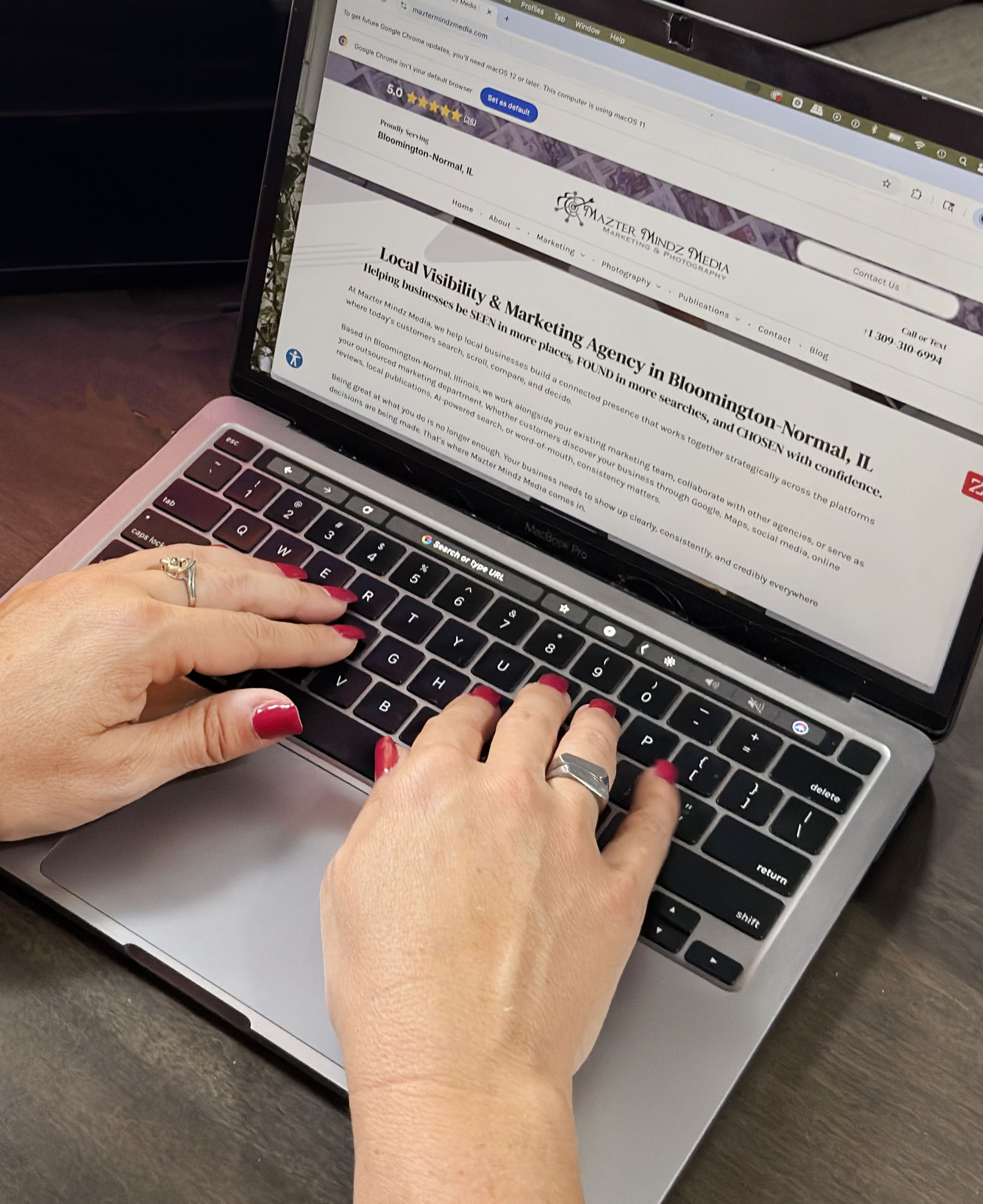 Hands typing on a laptop with a webpage open, red nails visible.