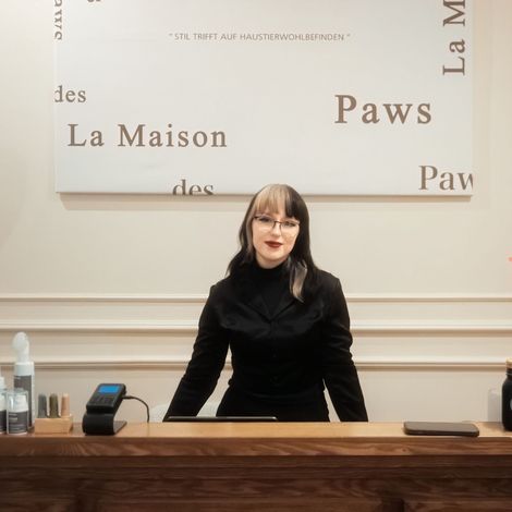 Eine Frau steht hinter einer Theke vor einem Schild mit der Aufschrift „Pfoten“