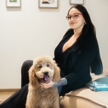 Eine Frau sitzt mit einem Hund auf einer Couch