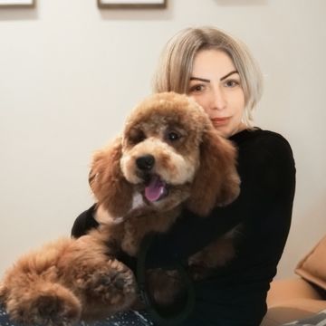 Eine Frau hält einen kleinen braunen Hund im Arm