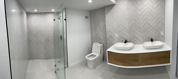 Modern bathroom with a glass shower, toilet, and a double sink vanity with wood paneling.
