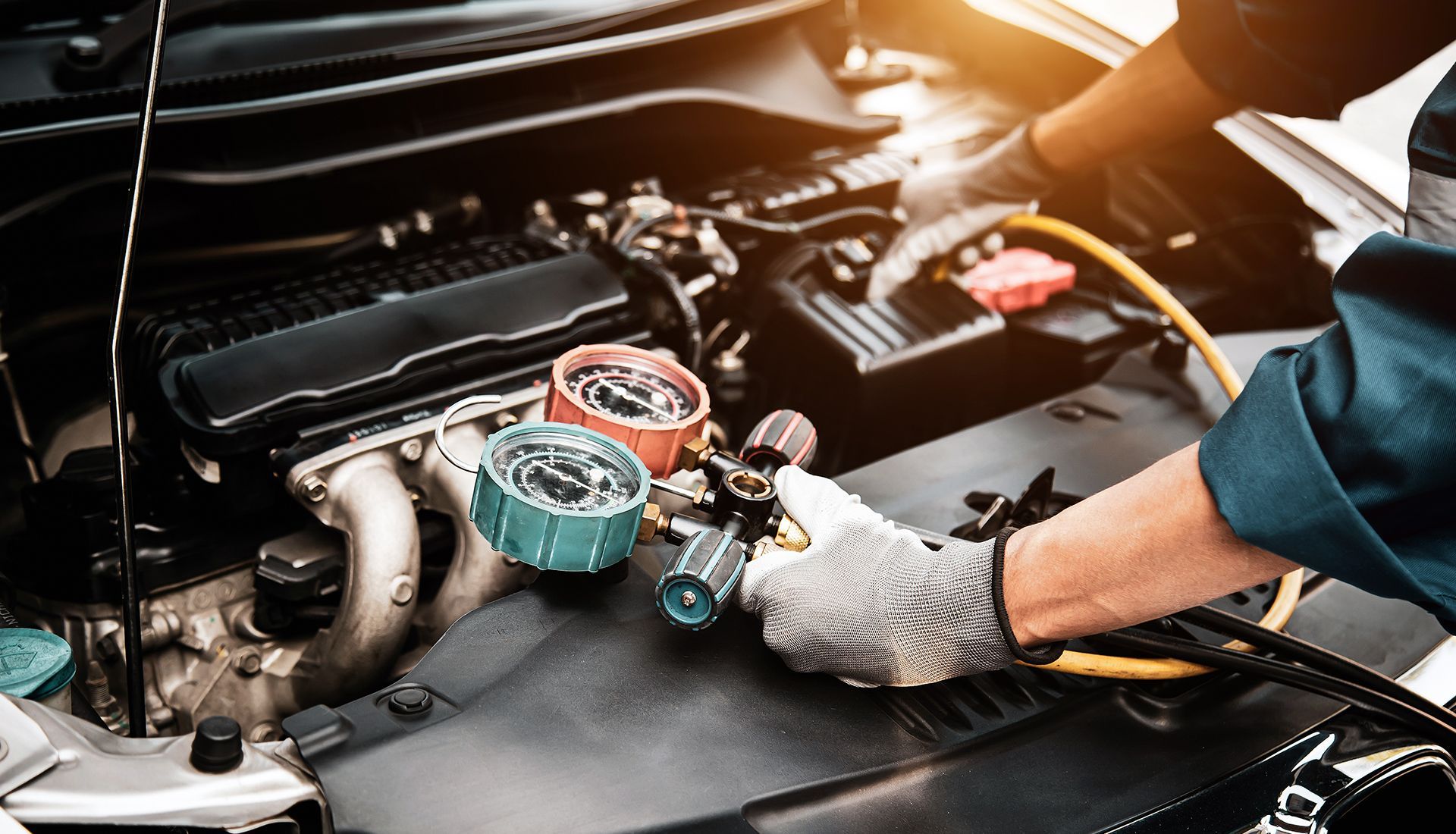 Mechanic working on car engine, using gauges.