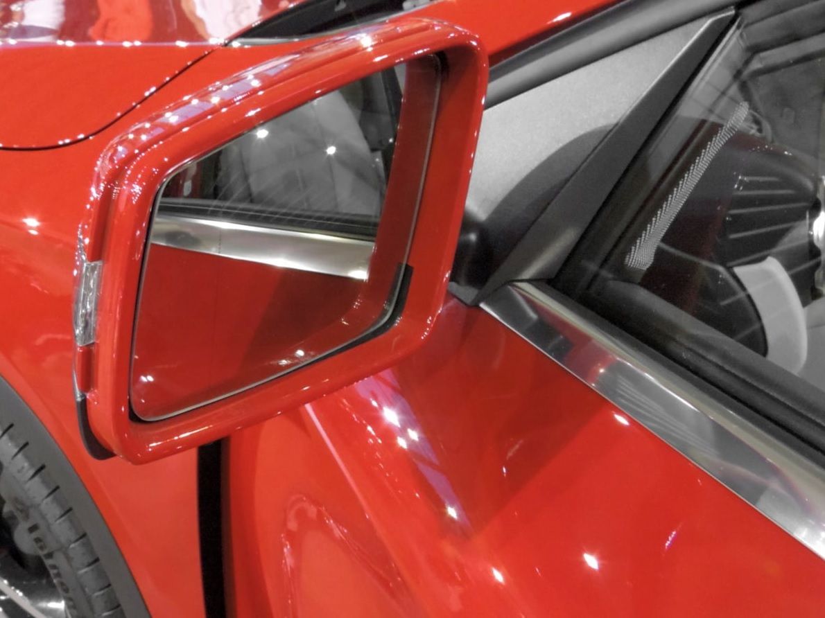 Red car side mirror and window with black interior visible