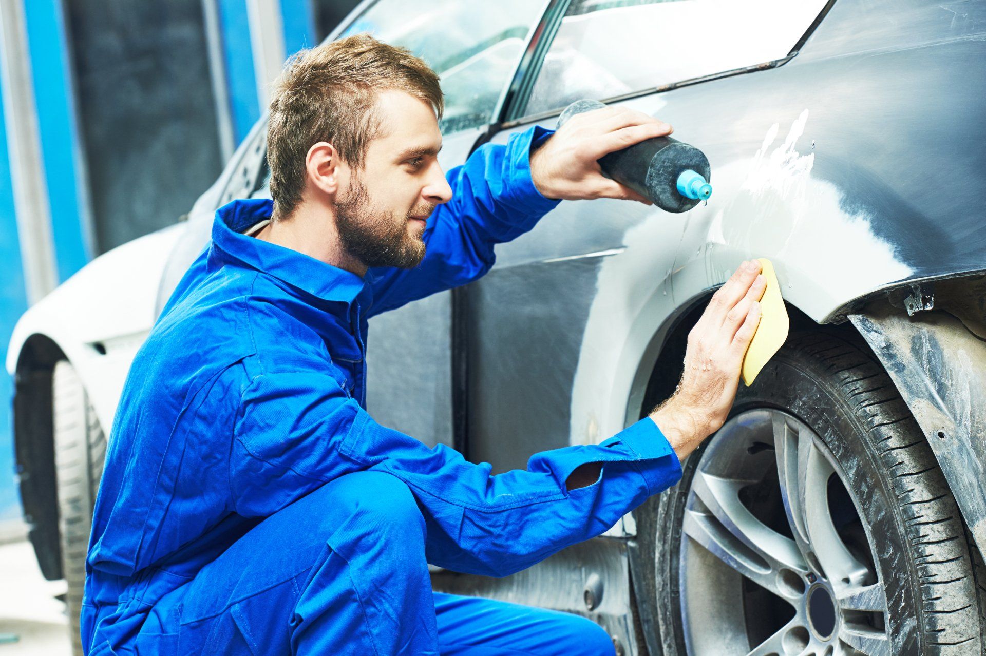 Mechanic fixing dent on vehicle
